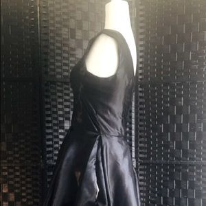 High low black dress with printed hummingbirds on a teal background.